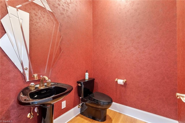 bathroom with hardwood / wood-style flooring, toilet, and sink