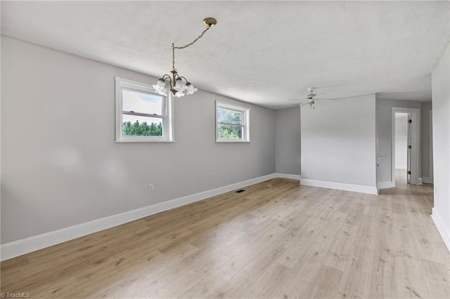 spare room featuring light hardwood / wood-style flooring and ceiling fan with notable chandelier