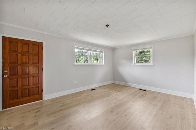 empty room featuring ornamental molding and light hardwood / wood-style flooring