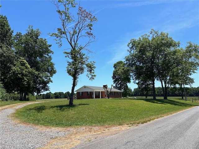 ranch-style home featuring gravel driveway and a front yard