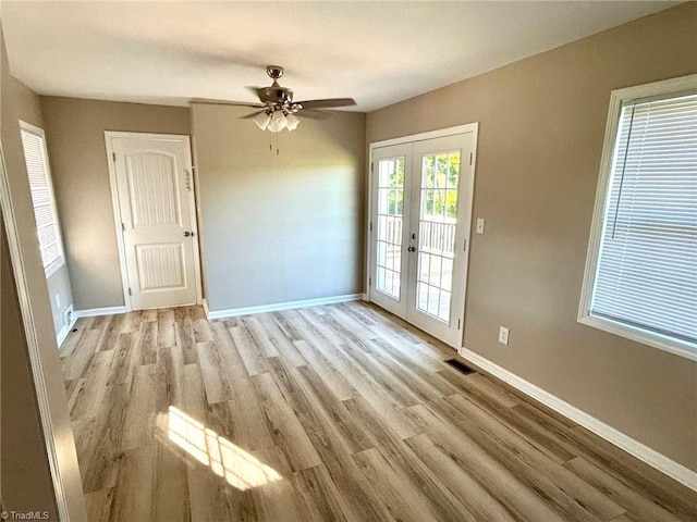 spare room with french doors, light wood-style flooring, baseboards, and a ceiling fan