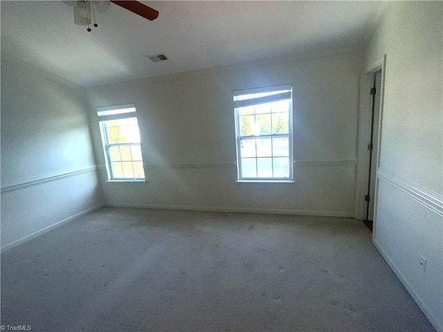carpeted empty room with visible vents, baseboards, and ceiling fan
