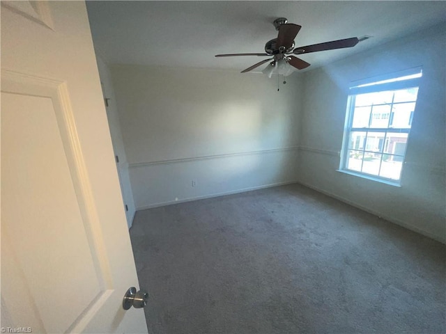 carpeted spare room with a ceiling fan
