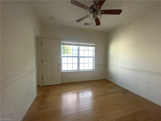 spare room with ceiling fan, visible vents, and wood finished floors
