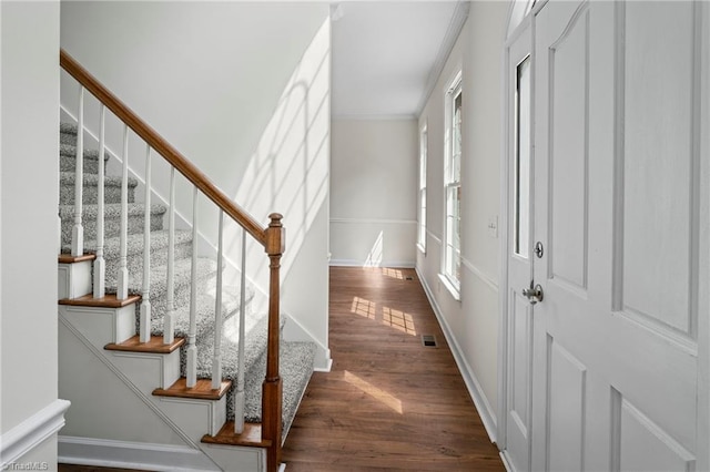 entryway with dark wood-type flooring and ornamental molding