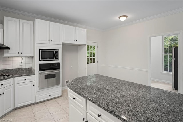 kitchen with appliances with stainless steel finishes, white cabinetry, dark stone countertops, and backsplash