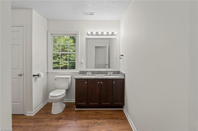 bathroom with toilet, hardwood / wood-style floors, vanity, and a textured ceiling