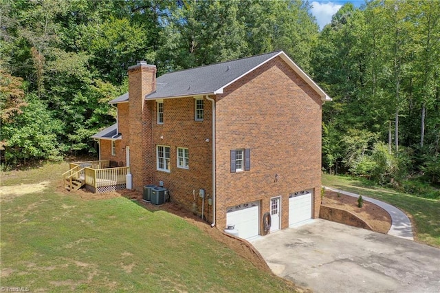 view of side of home with a deck, a yard, a garage, and central AC unit