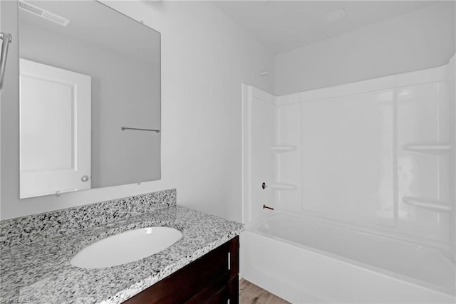 bathroom featuring vanity, wood-type flooring, and washtub / shower combination