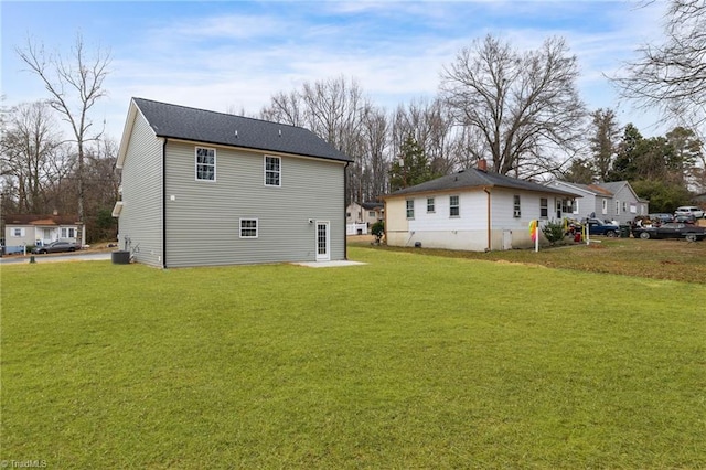 rear view of house featuring central AC unit and a lawn