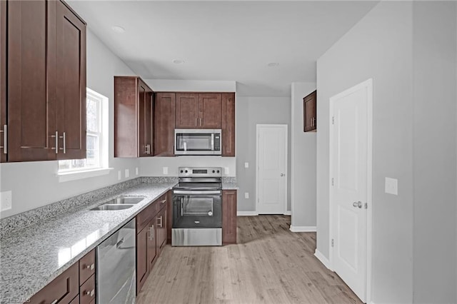 kitchen with dark brown cabinetry, light stone countertops, sink, appliances with stainless steel finishes, and light wood-type flooring