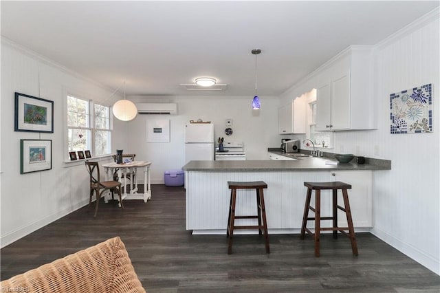 kitchen with white cabinets, decorative light fixtures, white appliances, and kitchen peninsula