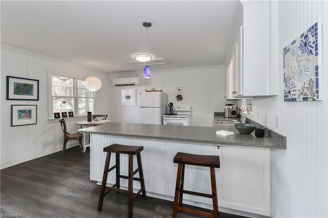 kitchen with white appliances, dark wood-type flooring, kitchen peninsula, a wall mounted AC, and white cabinetry