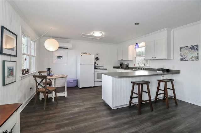 kitchen with plenty of natural light, white appliances, kitchen peninsula, decorative light fixtures, and white cabinetry