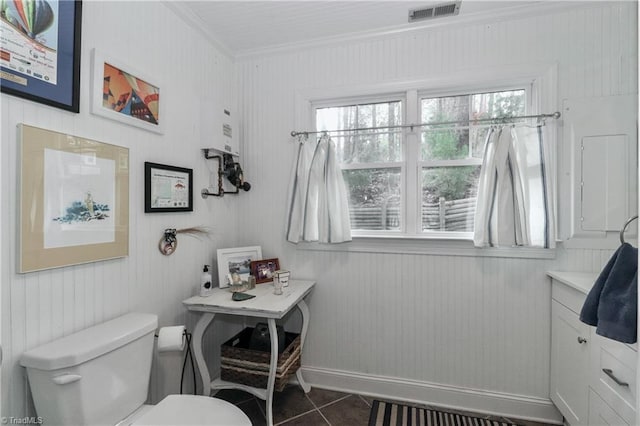 bathroom featuring tile patterned flooring, toilet, crown molding, and water heater