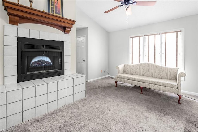 living room with a tiled fireplace, vaulted ceiling, ceiling fan, and carpet