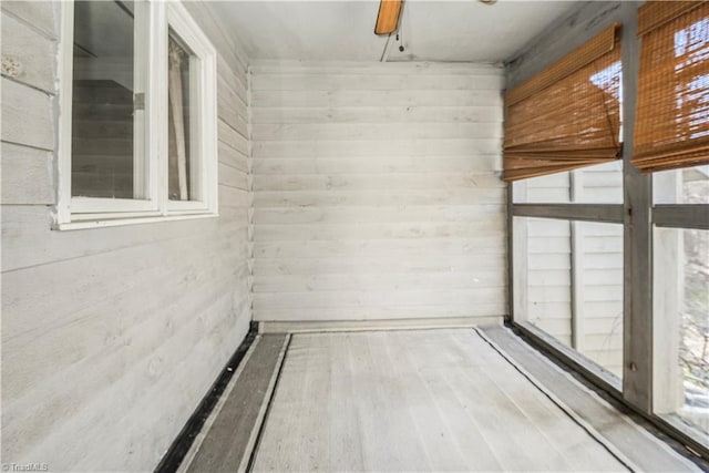 spare room featuring wood-type flooring, wooden walls, and ceiling fan