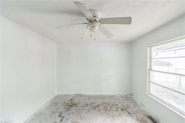 unfurnished room featuring a textured ceiling, a wealth of natural light, ceiling fan, and visible vents