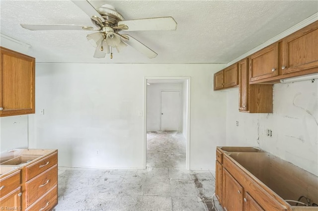 kitchen featuring brown cabinets, a textured ceiling, and ceiling fan
