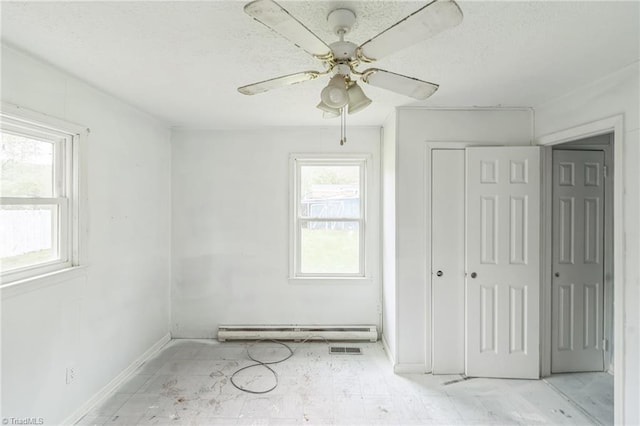 unfurnished bedroom featuring a baseboard heating unit, a closet, a textured ceiling, and baseboards