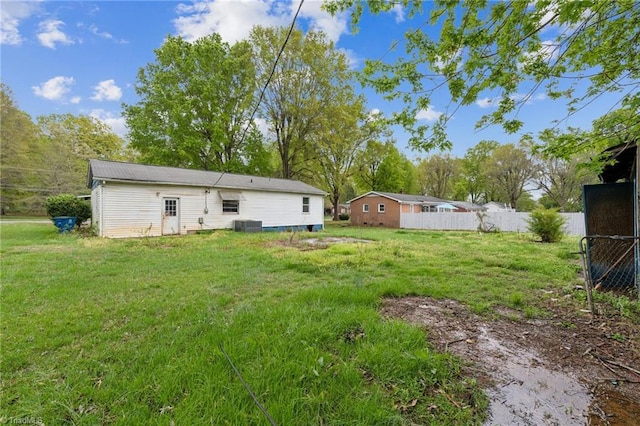 back of house featuring fence, a yard, and central AC unit