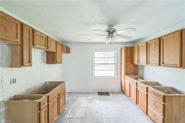 kitchen featuring brown cabinetry, ceiling fan, a textured ceiling, and visible vents