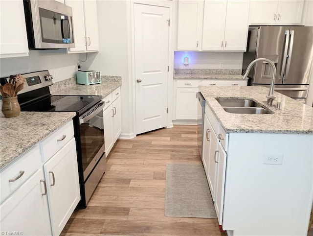 kitchen with a kitchen island with sink, a sink, white cabinets, appliances with stainless steel finishes, and light wood-type flooring