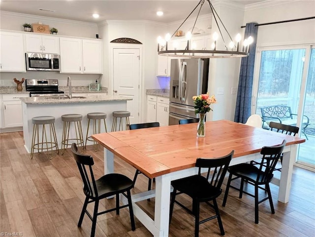 dining area with light wood-type flooring, an inviting chandelier, and crown molding