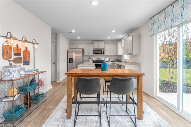 kitchen with light wood-type flooring, stainless steel appliances, and a breakfast bar area