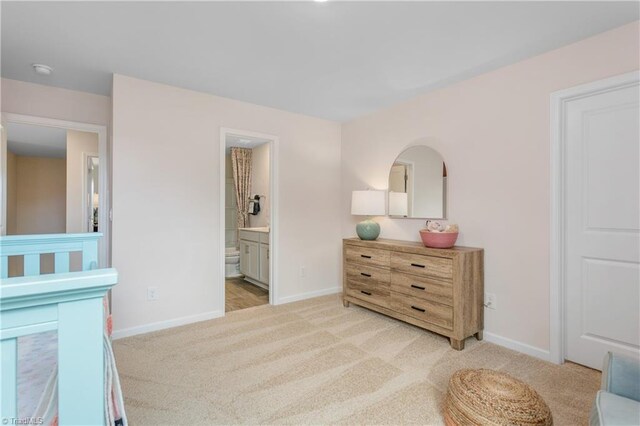 bedroom featuring connected bathroom, a nursery area, and light colored carpet