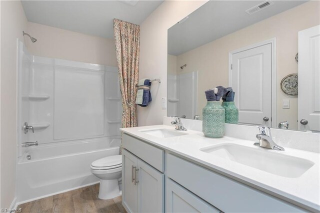 full bathroom with toilet, hardwood / wood-style floors, vanity, and washtub / shower combination