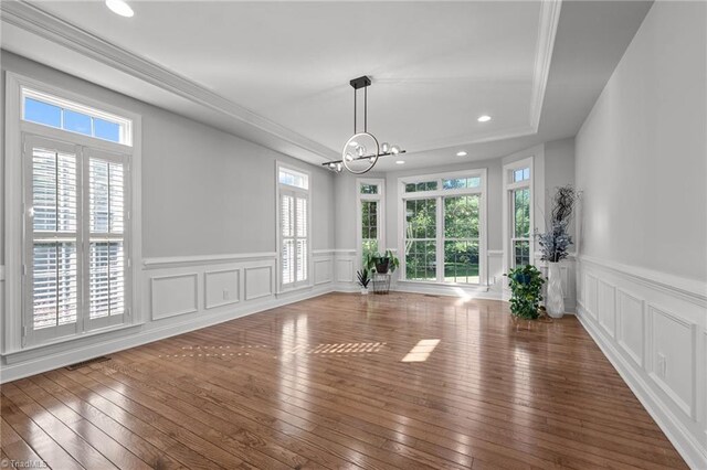 8501 Julina Dr, Oak Ridge, NC 27310 - unfurnished dining area featuring a chandelier, plenty of natural light, wood-type flooring, wainscoting, and a decorative wall