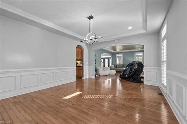 8501 Julina Dr, Oak Ridge, NC 27310 - unfurnished dining area featuring arched walkways, a wainscoted wall, wood-type flooring, crown molding, and a decorative wall