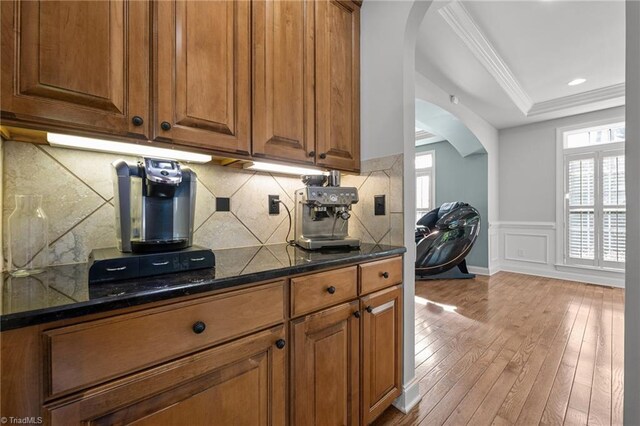 8501 Julina Dr, Oak Ridge, NC 27310 - kitchen with arched walkways, light wood finished floors, a raised ceiling, crown molding, and brown cabinets