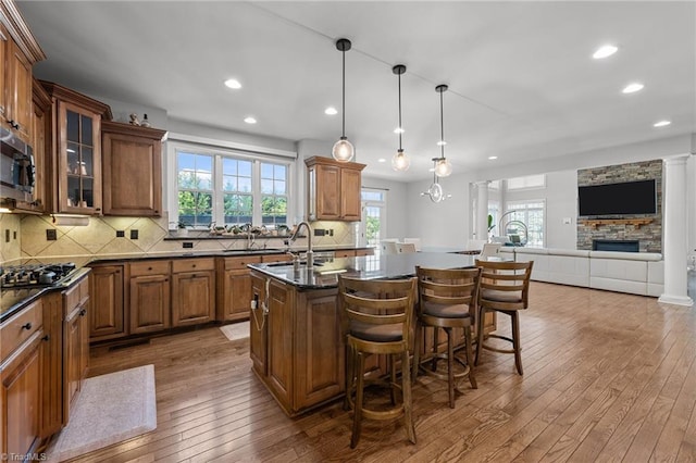 8501 Julina Dr, Oak Ridge, NC 27310 - kitchen with brown cabinetry, gas cooktop, wood-type flooring, a breakfast bar, and recessed lighting