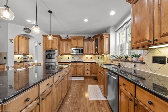 8501 Julina Dr, Oak Ridge, NC 27310 - kitchen with a sink, appliances with stainless steel finishes, brown cabinets, hardwood / wood-style floors, and arched walkways