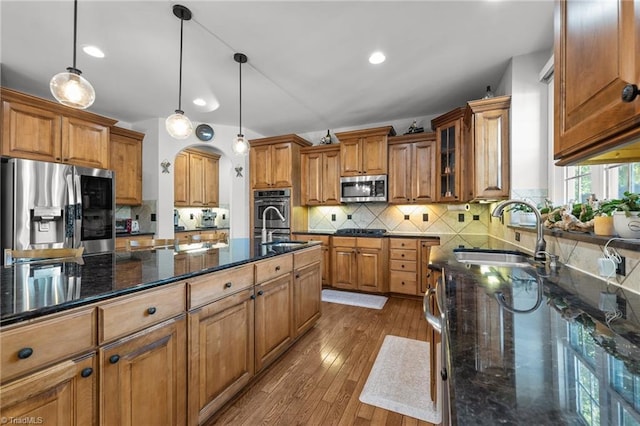 8501 Julina Dr, Oak Ridge, NC 27310 - kitchen with stainless steel appliances, a sink, brown cabinets, dark wood finished floors, and dark stone counters