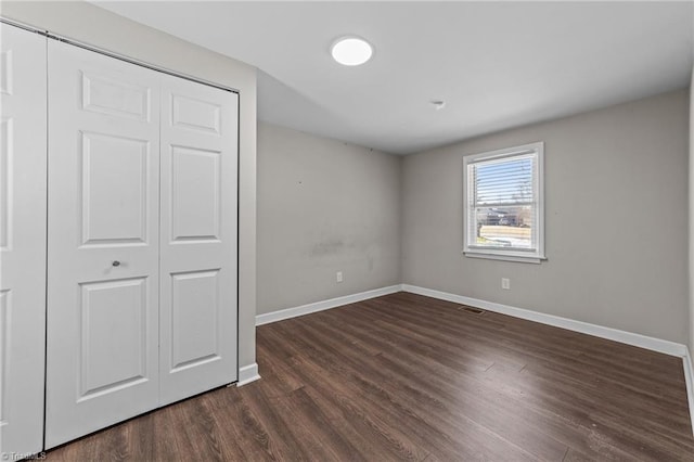 unfurnished bedroom with a closet and dark hardwood / wood-style floors