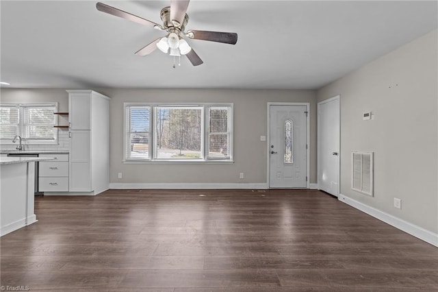 unfurnished living room featuring ceiling fan, dark hardwood / wood-style floors, a wealth of natural light, and sink