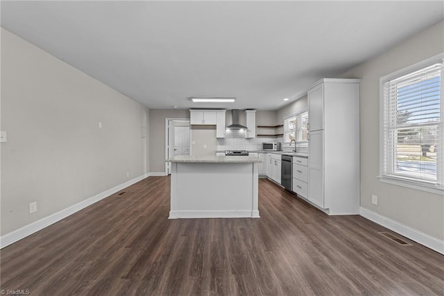 kitchen featuring stainless steel appliances, wall chimney range hood, white cabinetry, and a center island