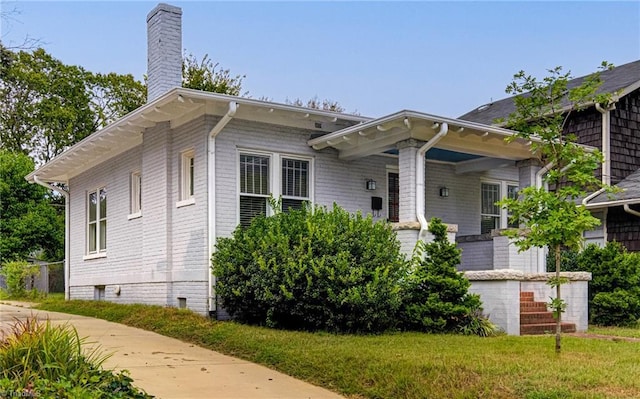 bungalow-style home with a front yard and a chimney