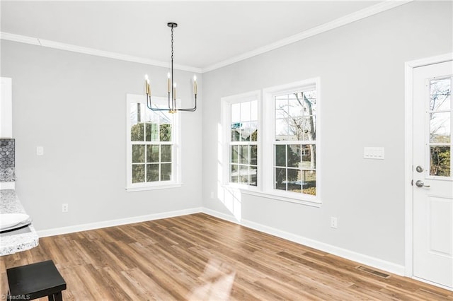 unfurnished dining area featuring an inviting chandelier, crown molding, and hardwood / wood-style floors