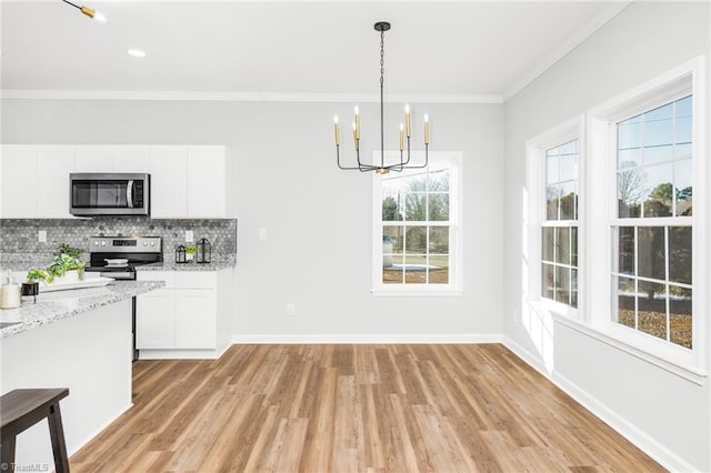 kitchen with stainless steel appliances, white cabinetry, backsplash, hanging light fixtures, and a chandelier