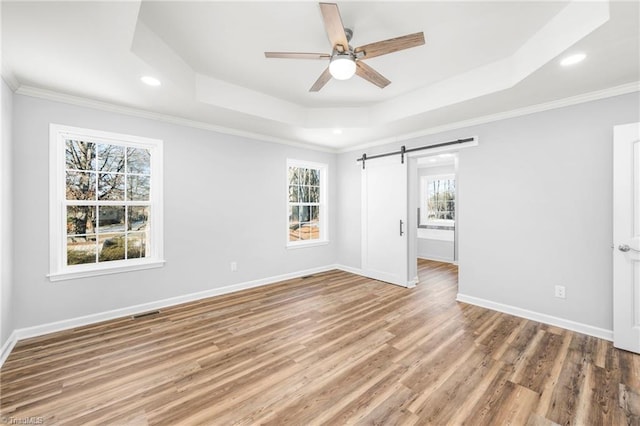 unfurnished bedroom featuring ceiling fan, crown molding, a barn door, and a tray ceiling