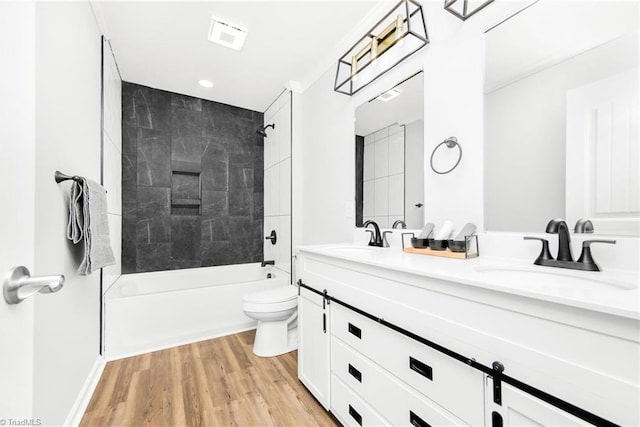 full bathroom with toilet, hardwood / wood-style flooring, tiled shower / bath, and vanity