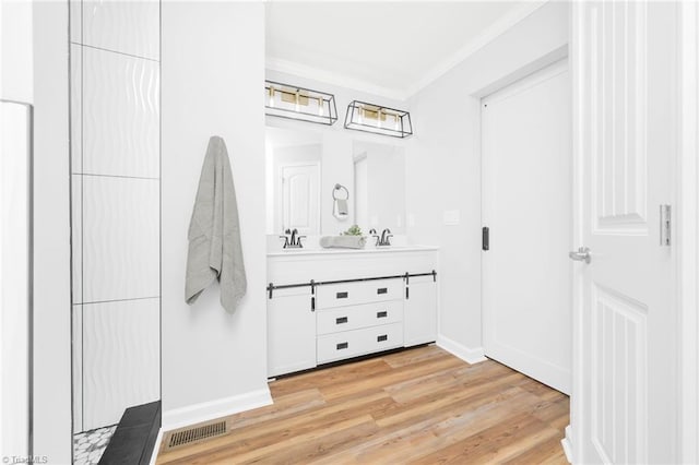 bathroom featuring hardwood / wood-style floors, crown molding, and vanity