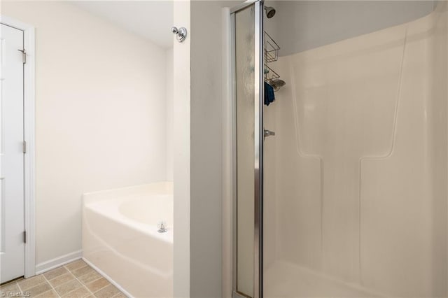 full bathroom with a garden tub, baseboards, and a stall shower