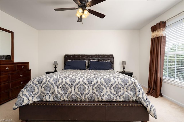 bedroom featuring light colored carpet, baseboards, and ceiling fan