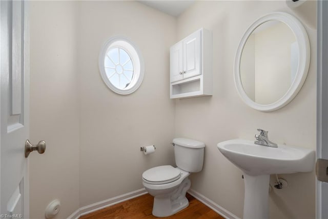 half bath featuring baseboards, toilet, and wood finished floors