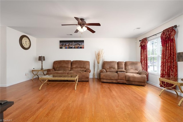 living area featuring baseboards, a ceiling fan, light wood-type flooring, and visible vents